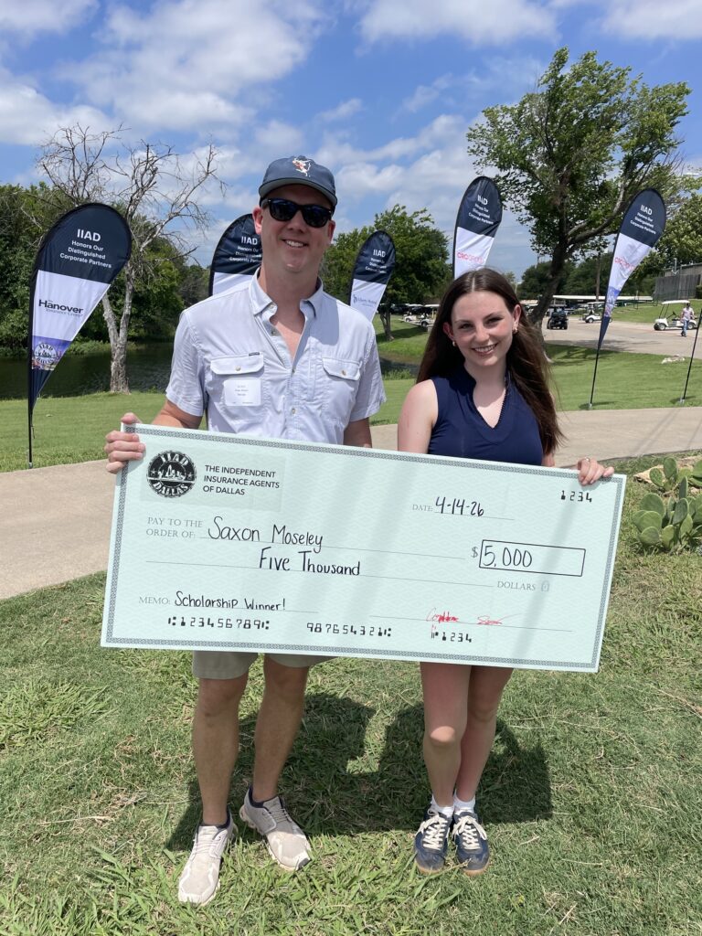 Drew Brown, CEO and Partner of TexCap Insurance, holds an enlarged check from IIAD next to Saxon Moseley, recipient of the Jim Millerman Agency Scholarship. The two are standing outside in the grass, both smiling.